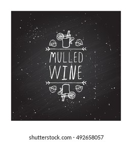 Hand-sketched typographic element with mulled wine, leaves and text on blackboard background. Mulled wine