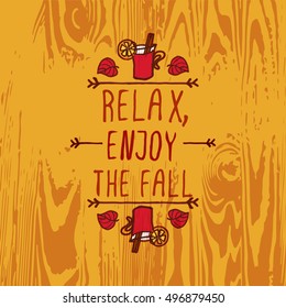 Hand-sketched typographic element with mulled wine, leaves and text on wooden background. Relax enjoy the fall