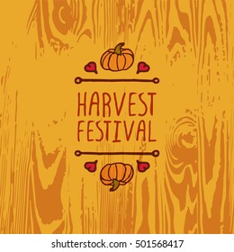 Hand-sketched typographic element with pumpkin, maple leaves and text on wooden background. Harvest festival