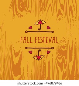 Hand-sketched typographic element with umbrella, hearts and text on wooden background. Fall festival