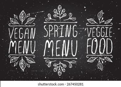 Handskizzierte typografische Elemente auf Chalkboard-Hintergrund. Veganisches Menü. Frühlingsmenü. Veggie-Essen. Restaurant-Etiketten. Geeignet für Anzeigen, Signaturen, Menü- und Webbanner-Designs