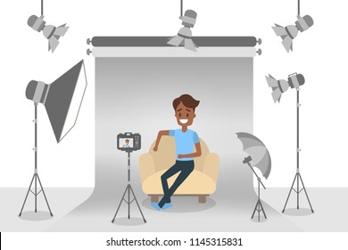 Handsome african american man in blue t-shirt and black jeans making photoshoot on the grey background with various equipment around such as softbox and camera. Isolated flat vector illustration