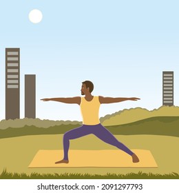 Handsome african american man practicing yoga, performing Virabhadrasana II or Warrior 2 pose outside the city on a sunny cloudless day