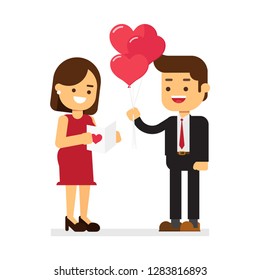 Handsome elegant guy is presenting a gift card and balloons to his beautiful girlfriend and smiling. Valentine's Day