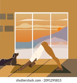 Handsome fit man practicing yoga indoors at the sunset, standing in Downward Facing Dog or Adho Mukha Shvanasana Pose on a yoga mat with a dog sitting next to him. The view of the sea and mountains.