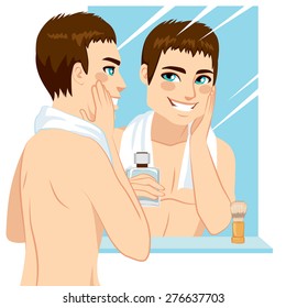 Handsome man applying after shave in his face in front of mirror
