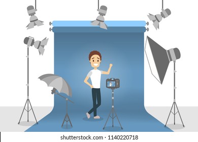 Handsome man in white t-shirt and black jeans making photoshoot on the gblue background with various equipment around such as softbox and camera. Isolated flat vector illustration