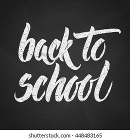 Handwritten Back to school words over black chalkboard.