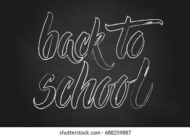 Handwritten Back to school words over black chalkboard.