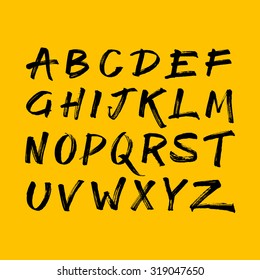 Handwritten calligraphic black alphabet written with brush pen on yellow background