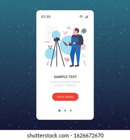 handyman worker with screwdriver and cutting pliers blogger recording online video with digital camera on tripod social network blogging concept full length smartphone screen mobile app copy space