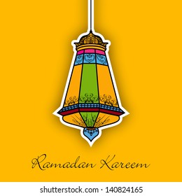 Hanging colorful Intricate Arabic lamp on yellow background for Ramadan Kareem.