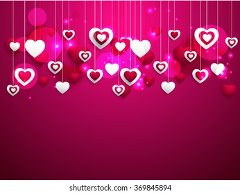 Hanging shiny pink heart on pink background.
