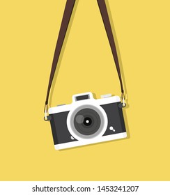 hanging vintage camera with strap on yellow background