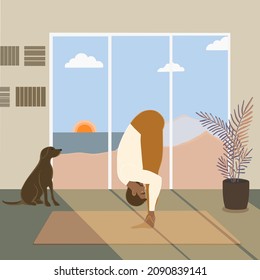 Hansome sporty African American man practicing yoga at home with a dog, standing in Uttanasana or standing forward bend pose at home with beautiful view on sunrise, sea, and mountains on summer sunny 