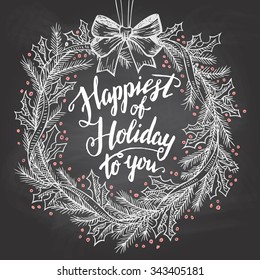 Happiest of holiday to you. Calligraphy quote with Christmas wreath on blackboard with chalk. Christmas chalkboard decor