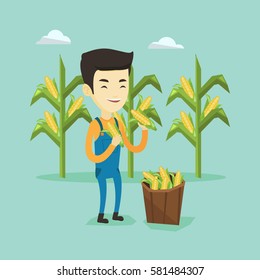 Happy asian farmer holding a corn cob on the background of corn field. Farmer collecting corn. Young smiling farmer standing near basket with corn. Vector flatdesign illustration. Square layout.