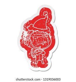 happy astronaut quirky cartoon distressed sticker of a wearing santa hat