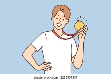 A happy athlete shows the gold medal he received. The guy won sports competitions. The boy is proud of his award. The winner who took the first place. The champion shows his achievement, the prize.