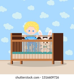 Happy baby boy in blue sleepwear standing in the wooden crib with soft toy white bunny rabbit isolated on clouds interior background. Vector illudtration in cartoon style. Flat children design.