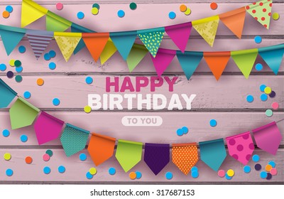 Happy Birthday card with colorful paper garlands and confetti on pink wooden background.