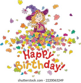 Happy birthday card with a funny little witch playing with flying and swirling colorful leaves, vector cartoon illustration isolated on a white background