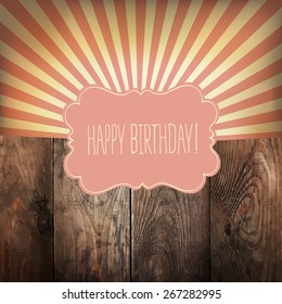 Happy Birthday greeting card with sunrays and vintage label. On wooden background