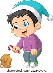 The happy boy is giving the candy cane to the baby rabbit of illustration