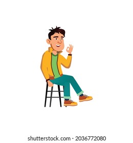 happy boy sitting on chair and gesturing ok cartoon vector. happy boy sitting on chair and gesturing ok character. isolated flat cartoon illustration
