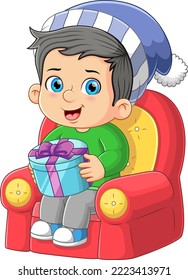 The happy boy is sitting on the sofa and holding the big santa gift of illustration