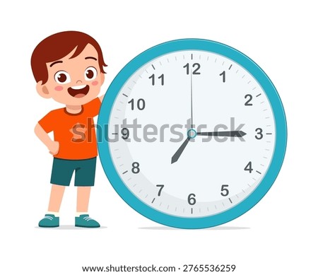 Happy boy standing next to a large blue wall clock smiling broadly a time education concept