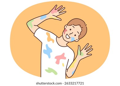 Happy boy with traces of paint on clothes and face after drawing lesson at school. Cheerful schoolboy in white t-shirt smeared with multi-colored paint looks at camera