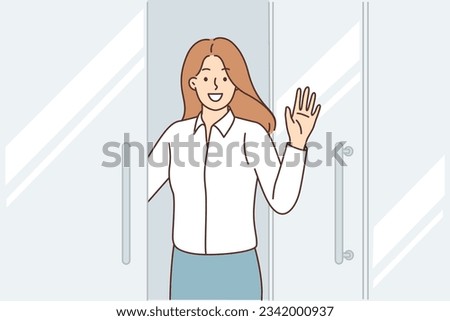 Happy business woman stands at door of business center, says welcome and waves hand inviting you to visit corporate office. Positive girl office employee says goodbye to colleagues before leaving