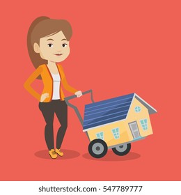 Happy caucasian woman pushing a shopping trolley with a house. Young smiling woman buying home. Woman using shopping trolley to transport a house. Vector flat design illustration. Square layout.