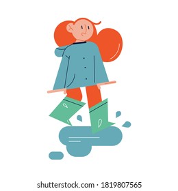 Happy child girl walking on paddles in rubber boots and enjoying autumn