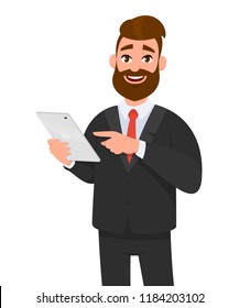 Happy confident business man holding or using a tablet computer. Business man standing isolated in white background gesturing hand using tablet PC. 