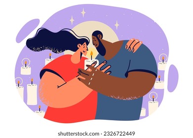 Happy couple hugging and holding burning candle spending romantic evening together for concept diversity and multiracial love. Multiracial young family enjoys privacy and intimacy.