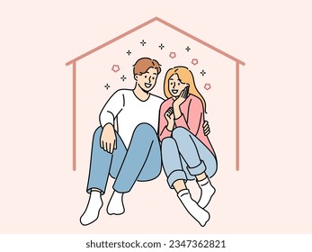 Una pareja feliz se sienta en una casa imaginaria soñando con hipotecas y comprando propiedad o alquilando un apartamento grande. Hombre y mujer abrazando dentro de la casa, usando los servicios del seguro inmobiliario