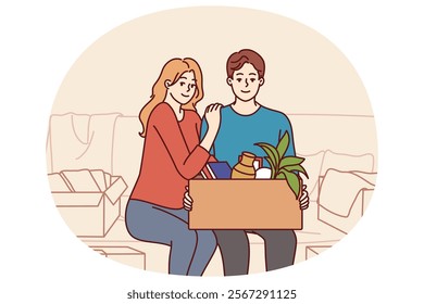 Happy couple is sitting on couch with cardboard box after moving into new house or buying own apartment. Family of man and woman smile happy about renting property in elite area and moving