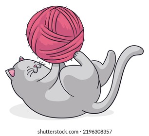 Happy and cute cat entertained with a pink and big ball of wool.