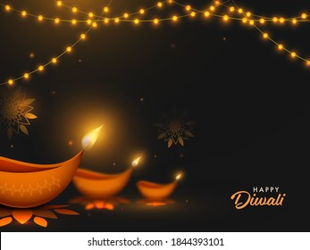 Happy Diwali Text With Illuminated Oil Lamps (Diya) And Lighting Garland Decorated On Black Background.