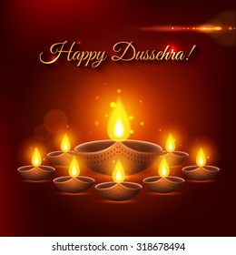 Happy Dussehra shining typographical background with candles, fire and blurred bokeh lights.