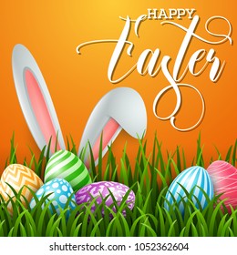 Happy Easter background with colored eggs and ears bunny in the grass on orange background