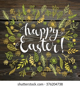 Happy Easter calligraphy on wood texture. Handwritten modern brush lettering with hand drawn leaves and flowers.