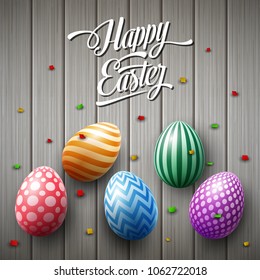 Happy Easter egg with confetti on wooden gray background