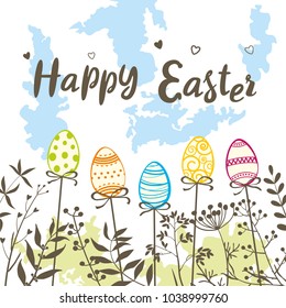 Happy Easter. Easter eggs and a congratulatory inscription against the sky and wild herbs.