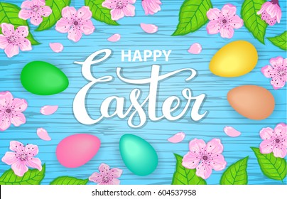 Happy easter greeting background with colorful eggs, flowers, green leaves and hand lettering on a wooden blue texture
