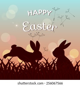 happy easter greeting card, seeds flying in the air and silhouettes of bunnies in the meadow at twilight