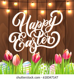 Happy Easter lettering with eggs, garland and tulip flowers in grass on rustic wooden background. Festive vector design. 