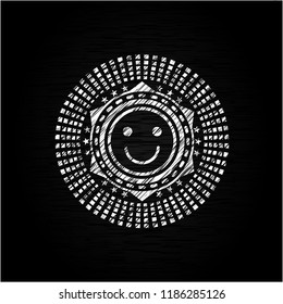 happy face icon inside chalkboard emblem on black board